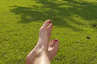 Eine Frau legt ihre Füße auf der Liege im Garten hoch