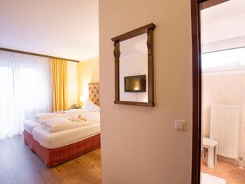 Ein Hotelzimmer im Hotel Agathawirt mit Doppelbett, einer Balkontür und einem Badezimmer