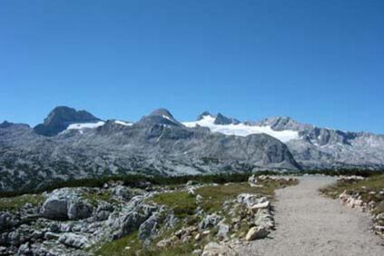 Ein Kiesweg führt zum Gipfel, rechts und links sind größere Steine und Felsen zu sehen.