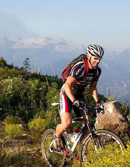 Drei Mountainbikefahrer fahren durch Sträucher den Berg hinauf