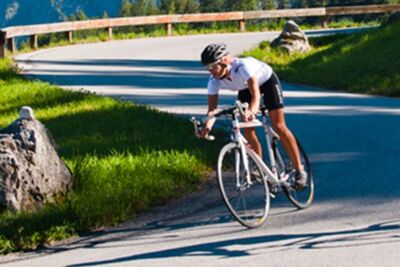 Ein Rennradfahrer fährt mit seinem Fahrrad eine Bergstraße hinunter