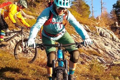 Eine Frau und ein Mann fahren mit dem Mountainbike einen Berg hinab