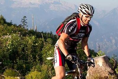 Drei Mountainbikefahrer fahren durch Sträucher den Berg hinauf