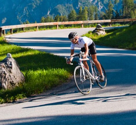 Ein Rennradfahrer fährt mit seinem Fahrrad eine Bergstraße hinunter