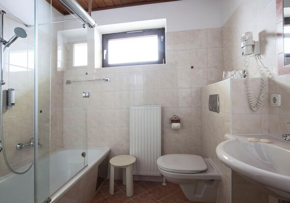 Ein helles Badezimmer mit Badewanne und einem Waschbecken im Landhotel Agathawirt