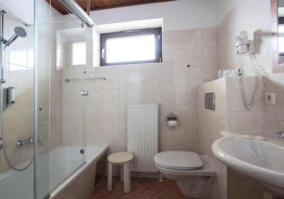 Ein helles Badezimmer mit Badewanne und einem Waschbecken im Landhotel Agathawirt