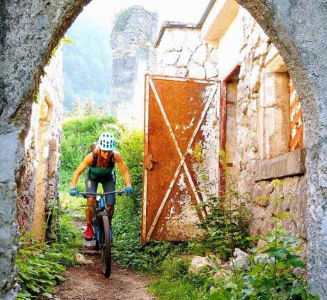 Eine Frau fährt mit dem Bike unter einer Ruine durch