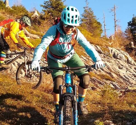 Eine Frau und ein Mann fahren mit dem Mountainbike einen Berg hinab