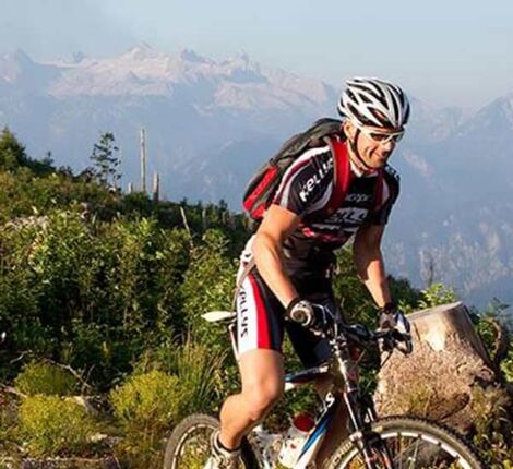 Drei Mountainbikefahrer fahren durch Sträucher den Berg hinauf