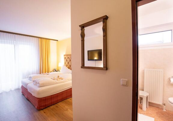 Ein Hotelzimmer im Hotel Agathawirt mit Doppelbett, einer Balkontür und einem Badezimmer