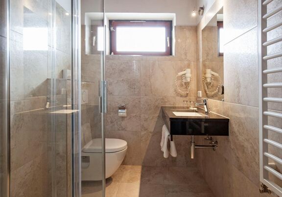 Badezimmer mit hellen Marmorfliesen und begehbarer Dusche im Hotel Agathawirt