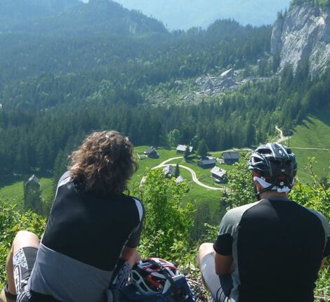 Ein Mann und eine Frau sitzen auf einem Berg und genießen die Aussicht auf den Bergalmen