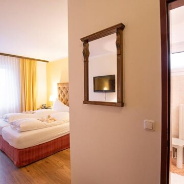 Ein Hotelzimmer im Hotel Agathawirt mit Doppelbett, einer Balkontür und einem Badezimmer