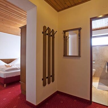 Ein kleiner Vorraum der ins Schlafzimmer mit einem Doppelbett und in ein Badezimmer führt