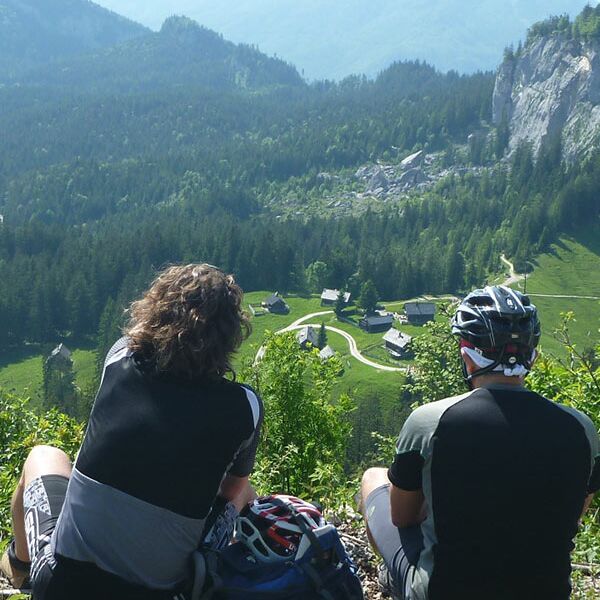 Ein Mann und eine Frau sitzen auf einem Berg und genießen die Aussicht auf den Bergalmen