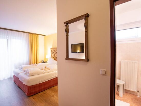 Ein Hotelzimmer im Hotel Agathawirt mit Doppelbett, einer Balkontür und einem Badezimmer