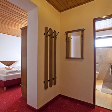 Ein kleiner Vorraum der ins Schlafzimmer mit einem Doppelbett und in ein Badezimmer führt