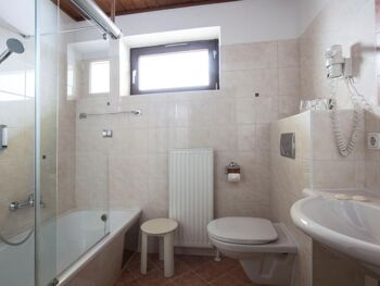 Ein helles Badezimmer mit Badewanne und einem Waschbecken im Landhotel Agathawirt