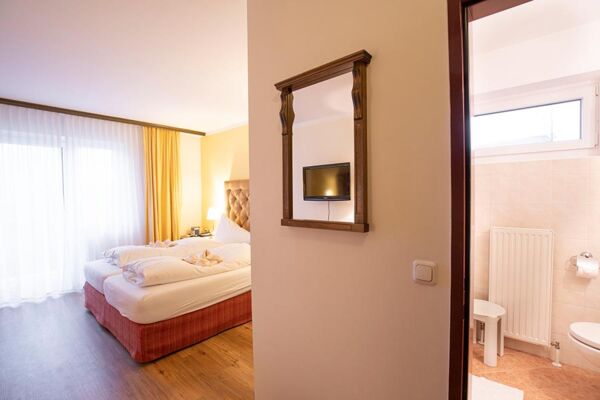 Ein Hotelzimmer im Hotel Agathawirt mit Doppelbett, einer Balkontür und einem Badezimmer