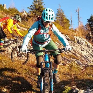 Eine Frau und ein Mann fahren mit dem Mountainbike einen Berg hinab