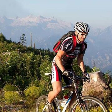 Drei Mountainbikefahrer fahren durch Sträucher den Berg hinauf