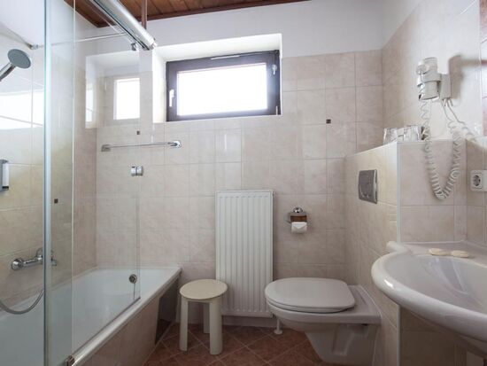 Ein helles Badezimmer mit Badewanne und einem Waschbecken im Landhotel Agathawirt