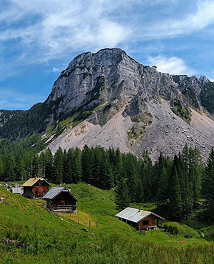 Several alpine huts stand on a hilly terrain in the Austrian Alps