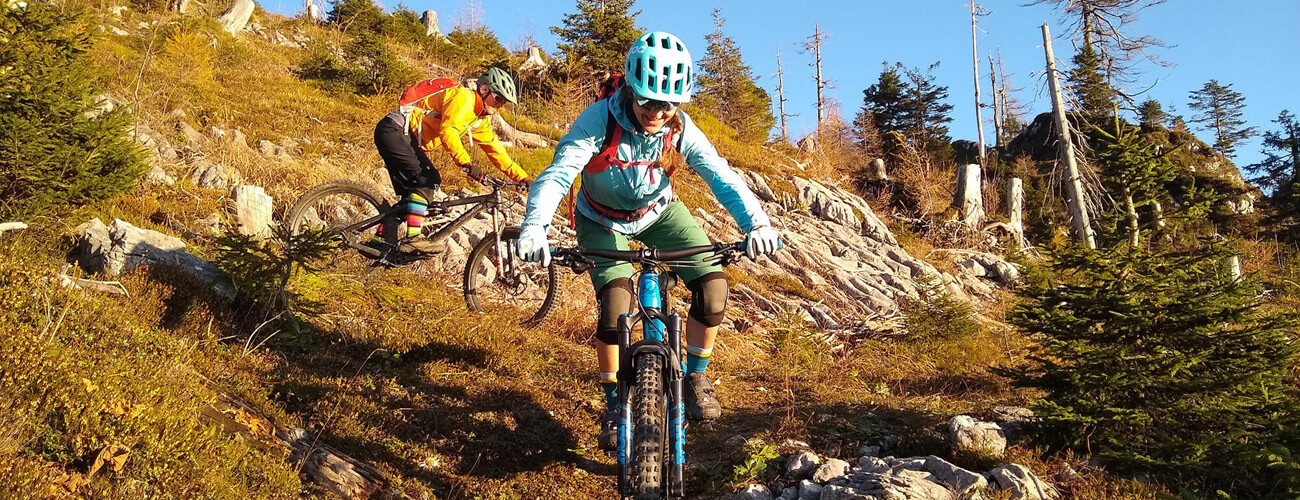 Zwei Mountainbiker fahren mit Mountainbikes an einem Herbsttag einen Bergtrail hinab